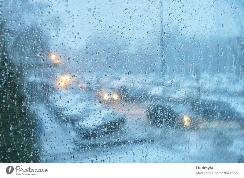 Rain drops on a transparent glass. Evening view of a city traffic. droplets cars jam vehicle transport glowing twilight storm street environment ride auto speed