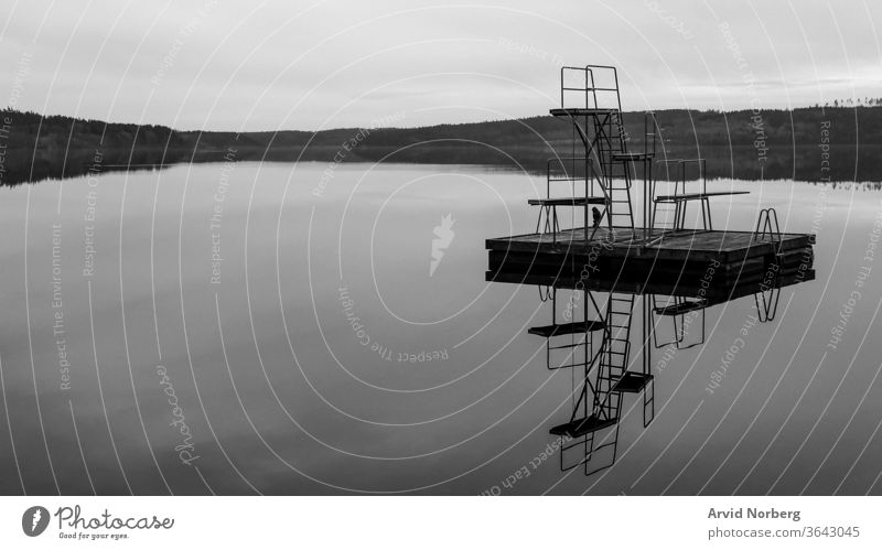 Black and white jetty jump tower with 1, 2 and 3 meter height in a rural lake in Sweden with reflection abstract amazing art background beach beautiful black
