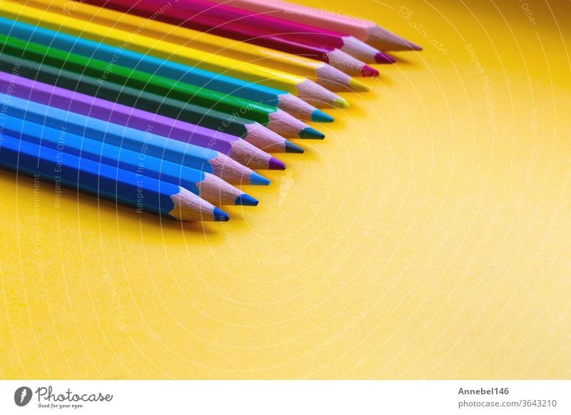 Colored pencils in Rainbow colors in a row on orange background, retro modern design space for text drawing school colorful education white yellow art green