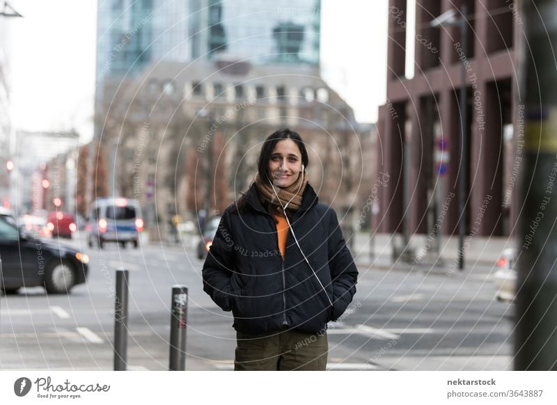 Attractive Young Indian Woman Posing on Street Corner young woman Indian ethnicity music earphones medium shot audiobook listening focus on foreground