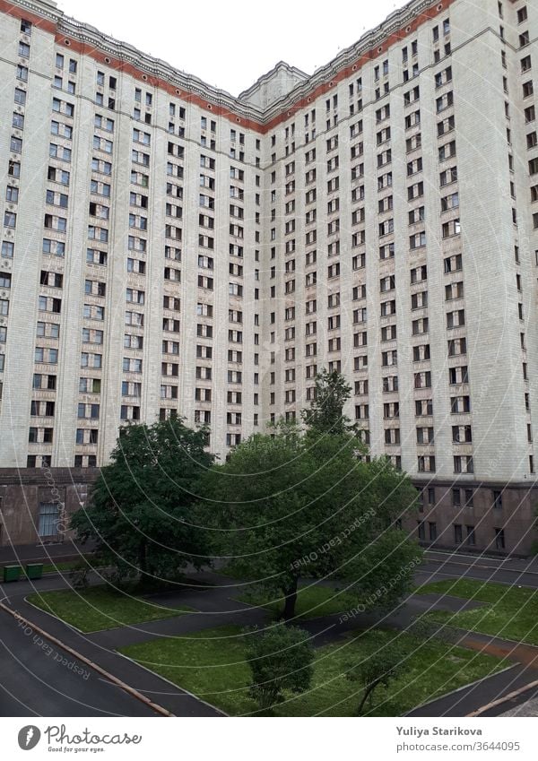 Photo of a tall block of flats with balconies in Moscow. Living apartments building architecture background. Common house object with gray walls and windows. Dormitory of Moscow State University.