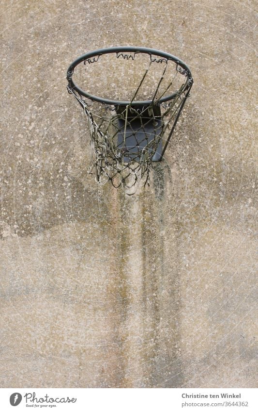 Old worn out basketball hoop with tattered net hangs on an old weathered concrete wall Basketball basket basketball net Net Broken shredded Concrete wall
