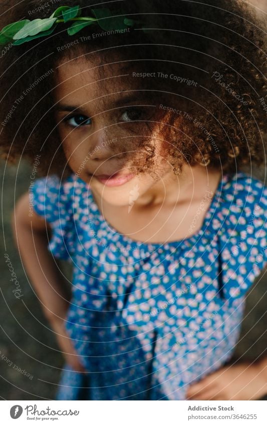 Serious little mulatto girl on blurred nature background black child serious portrait calm adorable summer style outfit unemotional curly hair cute sunlight