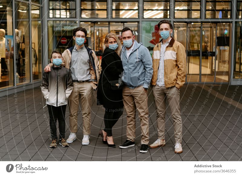 Positive friends in face masks against glass building relative respirator content positive door modern hand in pocket style coronavirus covid 19 boy child
