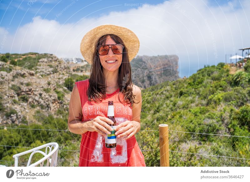 Happy woman with bottle of beer in tent traveler camp happy cheerful resort sunglasses cozy sunny leisure beverage relax content glad comfort summer mature