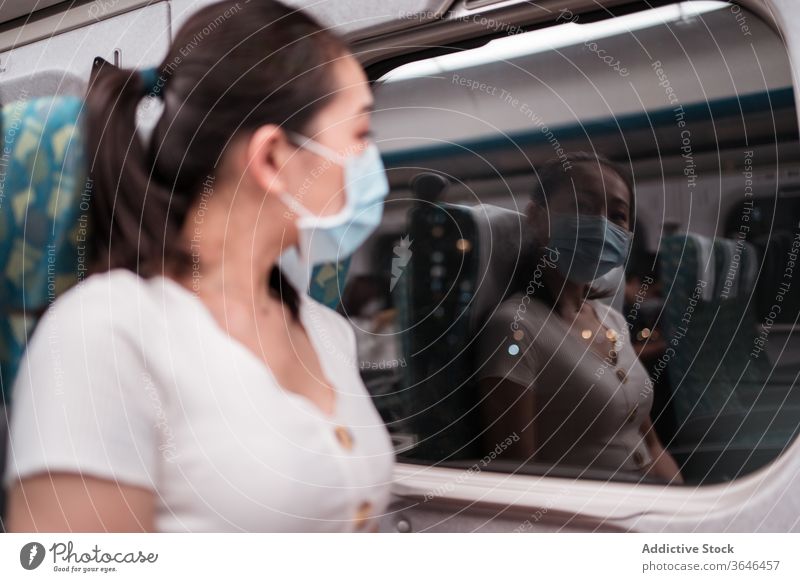 Calm female train passenger in respirator looking out window woman reflection cabin at night trip mask coronavirus comfort commute departure thoughtful