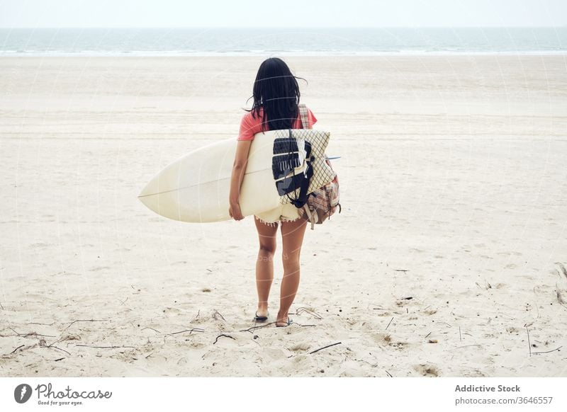 Anonymous female surfer walking on beach with surfboard woman sandy carry content sea casual seaside carefree activity young sporty tranquil lifestyle