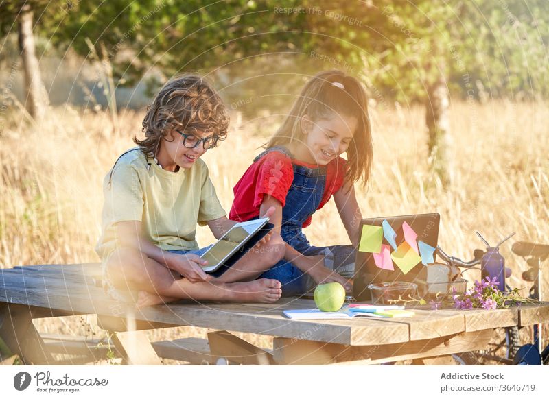 Ten-year-old boy and girl doing their homework in the field at a table casual clothing day mushrooms europe walking shorts girls full length brother lifestyle
