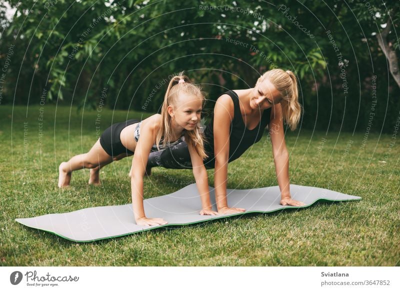 Mom and daughter play sports on the green grass near their home. Outdoor sports and fitness. Healthy sport lifestyle yoga outdoors mother home workout woman