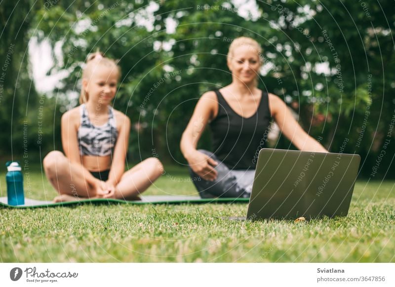 Mother and daughter practice online outdoors near their home during quarantine self-isolation during a pandemic. The family goes in for sports online from home together. Healthy lifestyle