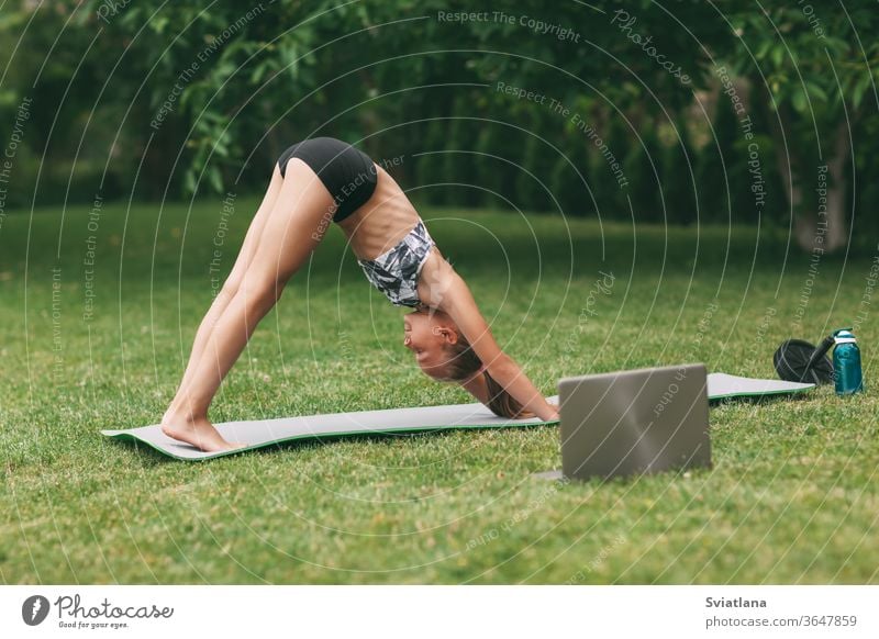 A teenage girl practices an online outdoor lesson near her home during quarantine self-isolation during a pandemic. Playing sports. Healthy lifestyle yoga