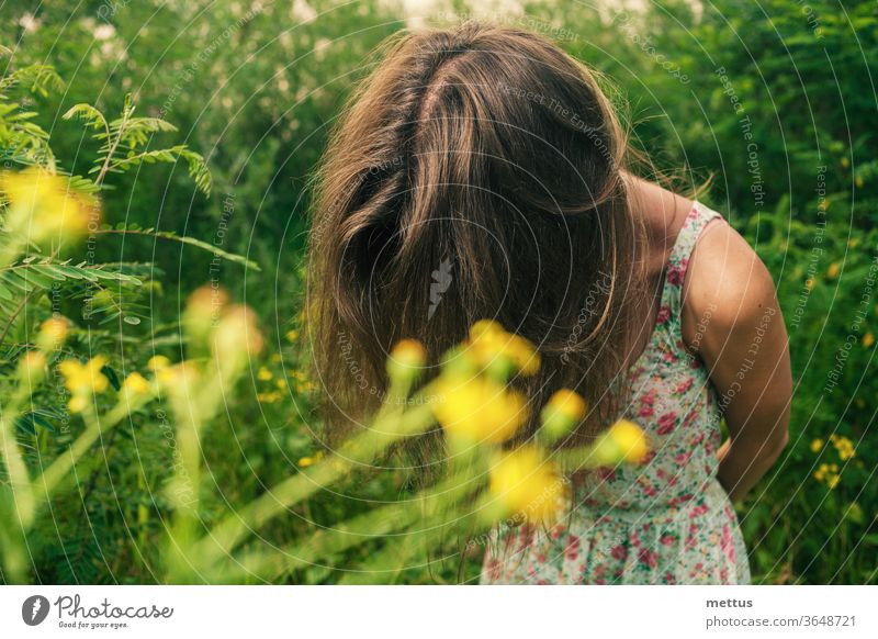 Beautiful blonde in a summer field is standing hiding her face by her hair for hiding emotions. dress candid shot beautiful fashion spring people young girl