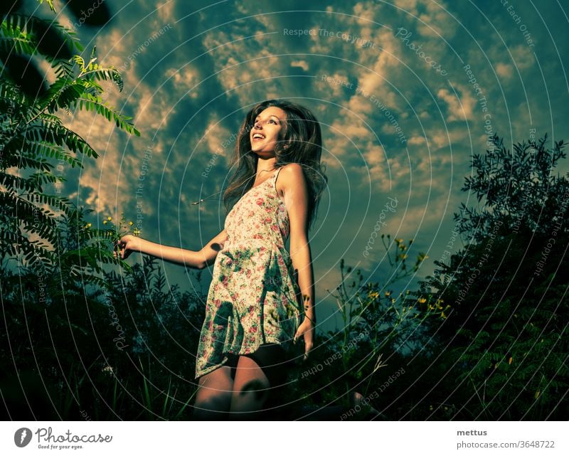 3648722 jolly girl is dancing in tall grass in front of the dramatic sky high jump in spring fields she is dressed in light summer dress dot photocase stock photo large