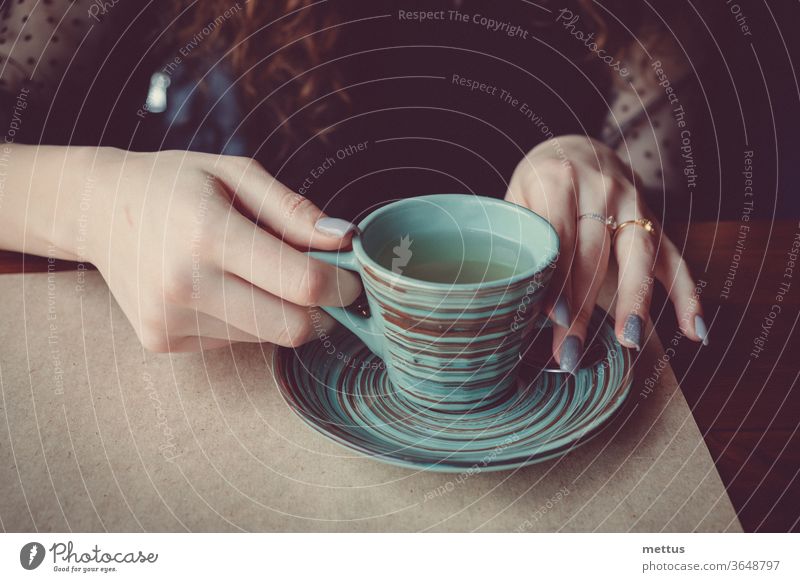 Vintage photo of the girls hands that hold a graceful ceramic cup covered with a pattern of colored circles female sitting drinking holding coffee cup mug
