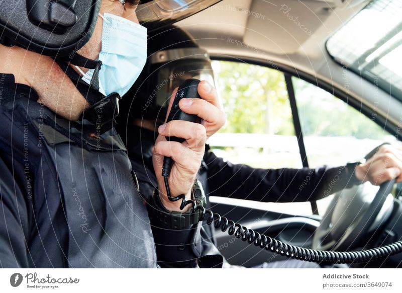 Anonymous police officers in squad car during service men talk radio set equipment gear safety protect professional uniform partner medical mask speak vehicle
