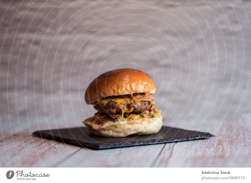 Delicious burger on slate board in cafe appetizing delicious serve hamburger cutlet tasty fast food cuisine wooden table sauce lunch junk food meal fresh meat
