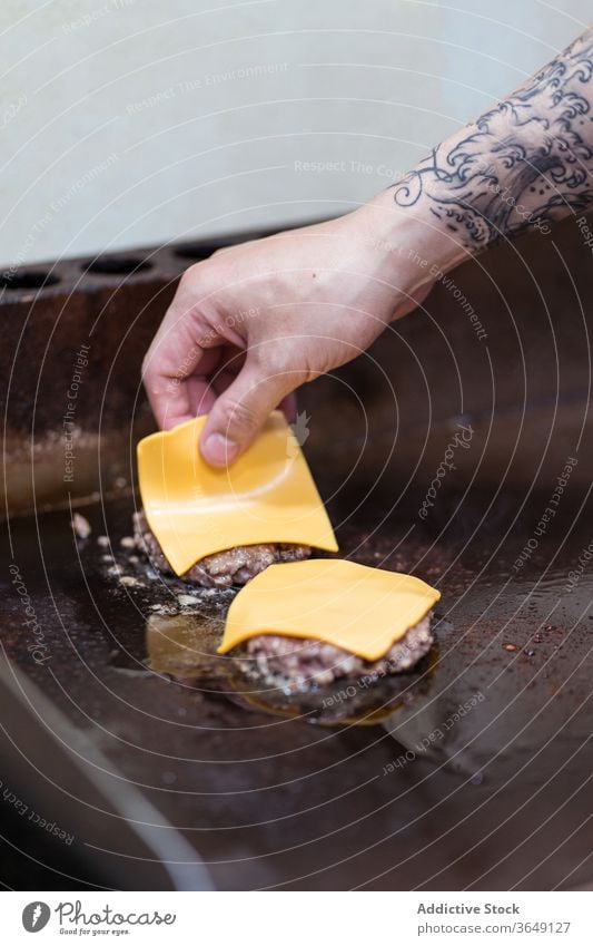 Crop male cook preparing burgers in cafe prepare cutlet cheese man add process tasty meat chef delicious fresh food gourmet cuisine work ingredient stove guy