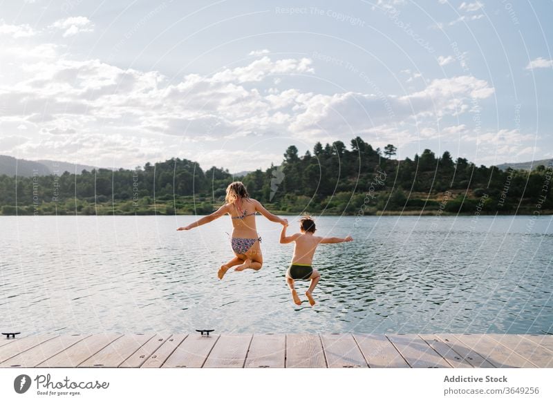 A Boy Walks Along A Wooden Pier On The Lake. A Child Is Standing