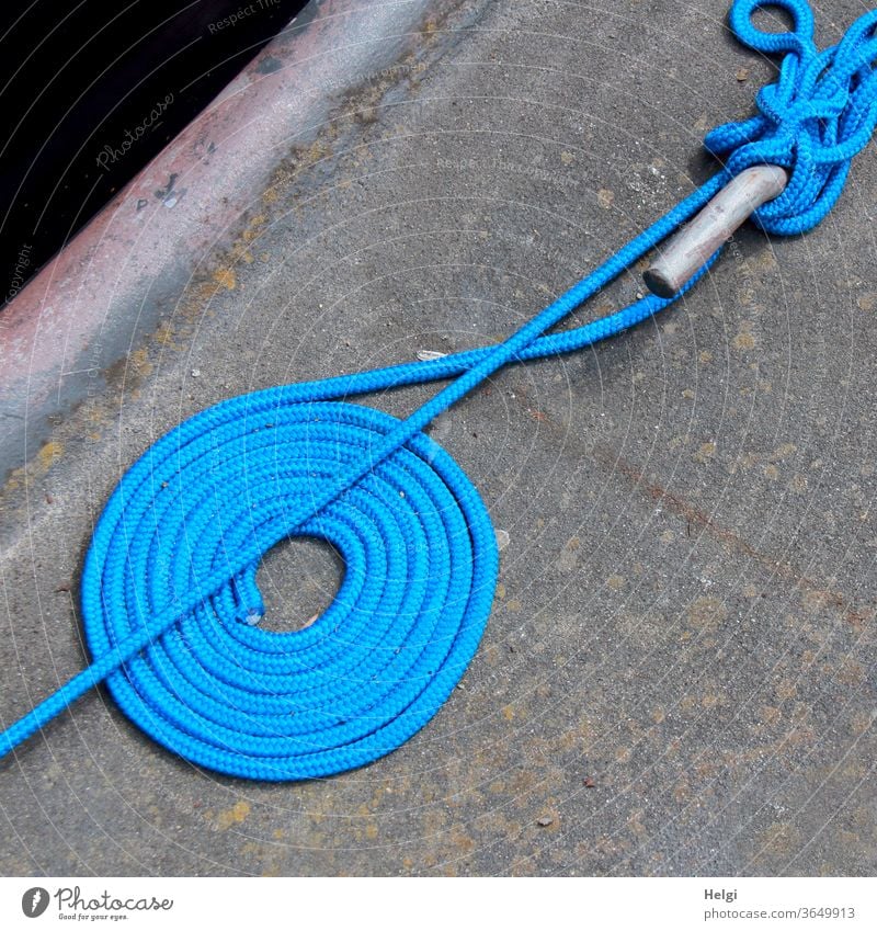 some order must be - blue fastening rope lies neatly rolled up and untidily wrapped around a pole on a quay wall Rope Dew Fastening coiled Wrapped around Rod