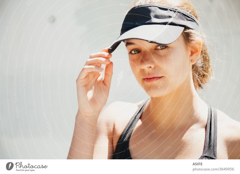 Portrait of a beautiful young sporty woman with visor cap in a warm day model fashion portrait face posing running isolated happy smiling runner wall gorgeous