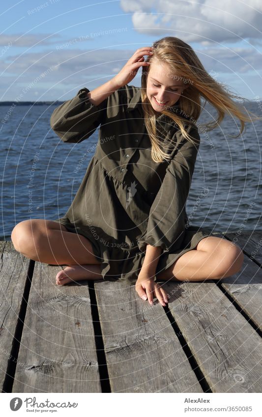 Full body portrait of a young, blond, barefoot woman on a wooden jetty in the sea Woman Young woman Blonde already Slim Long-haired windy Esthetic Summer Trip