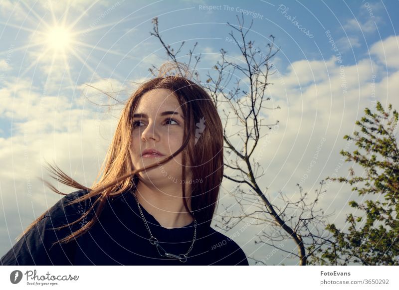 Girl is standing outdoors with blue sky, tree and sun portrait nature Person day beauty modern attractive girl real real person hair copy space teenager