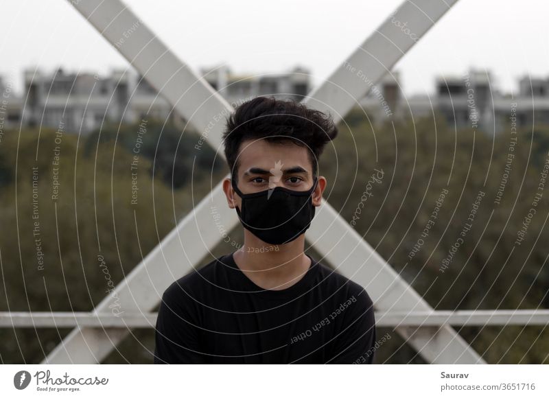 A young man wearing a protective face mask to avoid Coronavirus infection in a city. coronavirus covid 19 young adult new normal lifestyle summer portrait