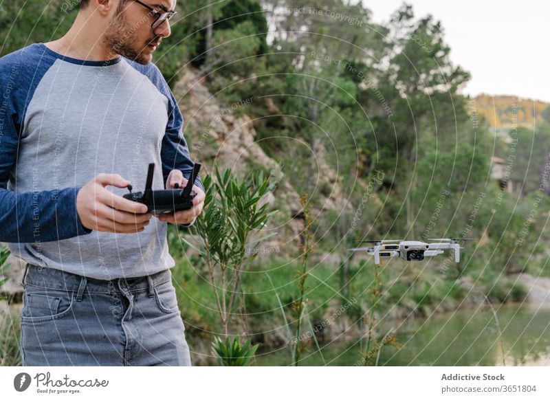 Focused man operating drone remotely control fly operate quadrocopter controller equipment unmanned flight male landscape mountain record video innovation