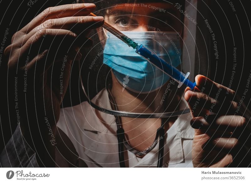 Female doctor with mask and shield holding vaccine in hands on black background 2020 air mask clinic corona epidemic corona virus coronavirus