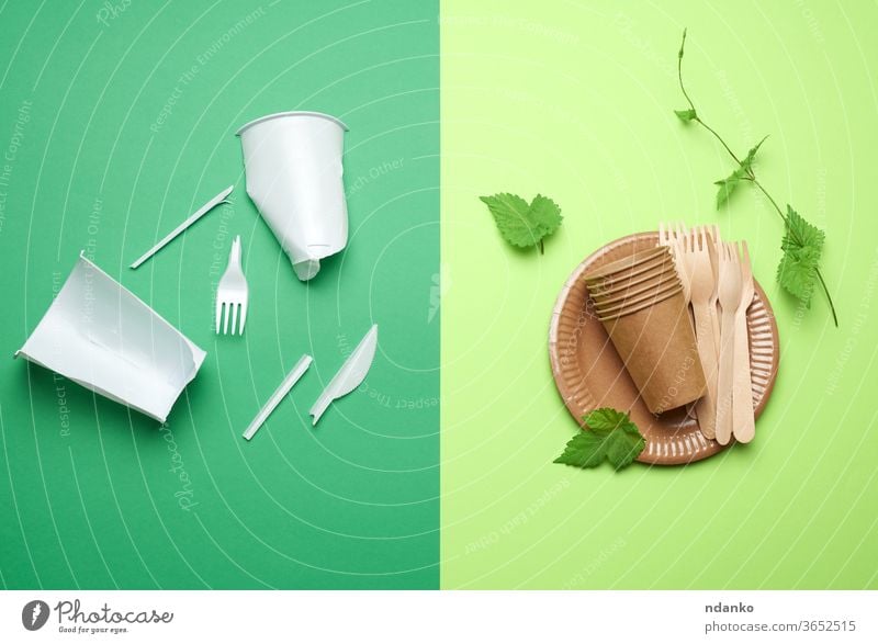 non-degradable plastic waste from disposable tableware and a set of dishes from environmental recycled materials on a green background opposition antipode trash