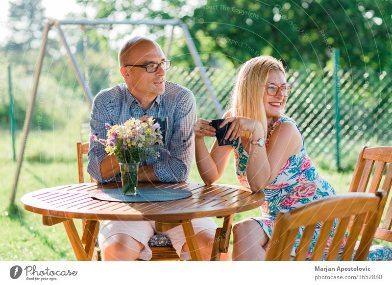 Young couple drinking coffee in the backyard in the morning adult casual caucasian cheerful communication country day enjoying evening family female garden girl