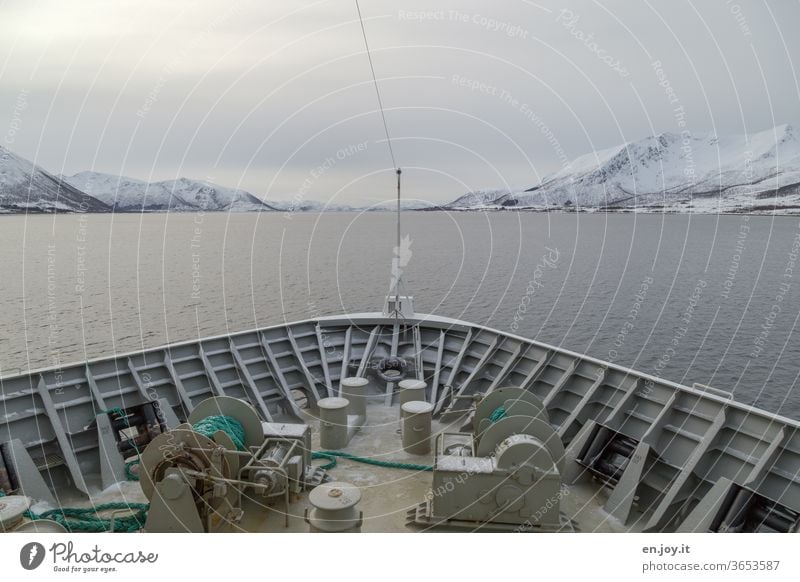 Bow of a ship with view of the Lofoten in Norway Navigation Ocean North Sea Lofotes Scandinavia Winter mountains Snow Sky Clouds Covered chill voyage vacation