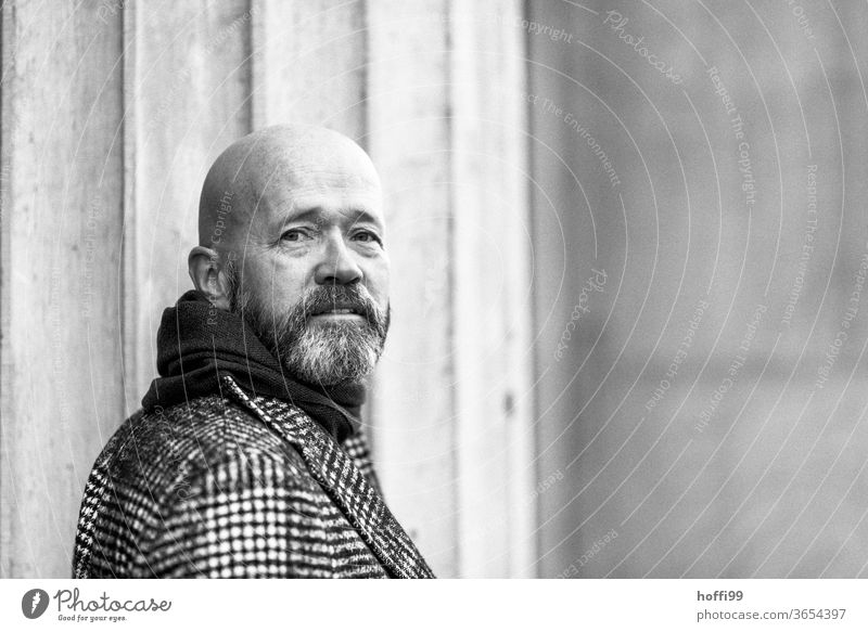 the man turns back and looks into the camera Man Facial hair Beard Coat Baldy Adults Masculine Human being portrait 1 Looking into the camera Exterior shot Face