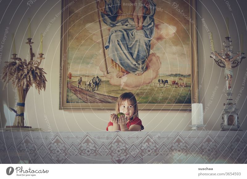 girl stands behind an altar in a chapel and holds an apple as a gift Chamansülz Holy Infancy Parenting tablecloth cross house of God Catholicism Candle holder