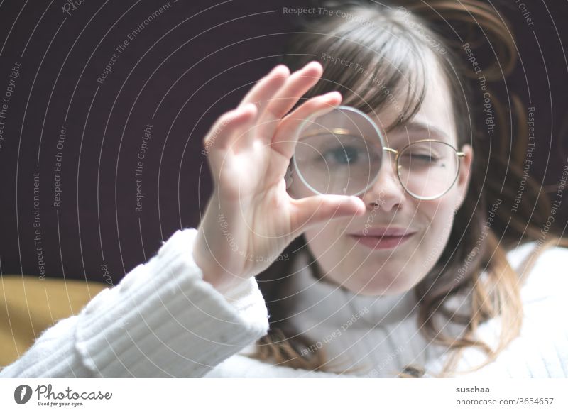 teenager holding a magnifying glass in front of her eyes Youth (Young adults) Face Eyeglasses hair Eyes Nose Mouth smile peep enlargement Magnifying glass