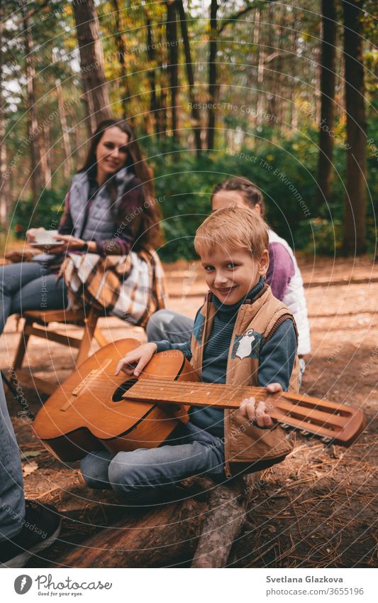 Happy family on a camping trip relaxing in the autumn forest. A boy holds a guitar in his hands fall nature father mother together fun happy people park smiling