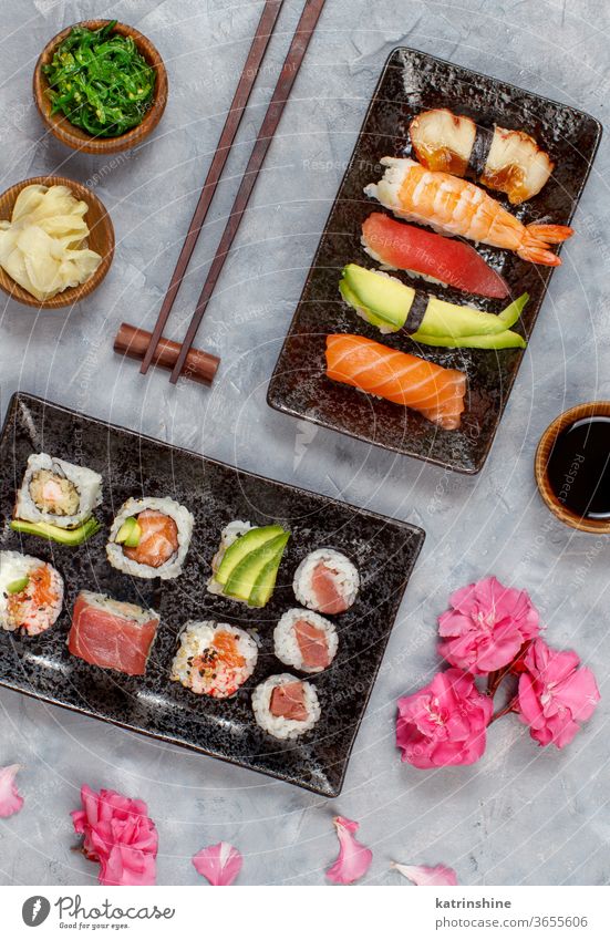 Sushi Set nigiri and sushi rolls on rectangular plates ready to eat eating Sashimi Rolls Maki sushi bar dinning Japanese Culture Seafood chopsticks grey flowers