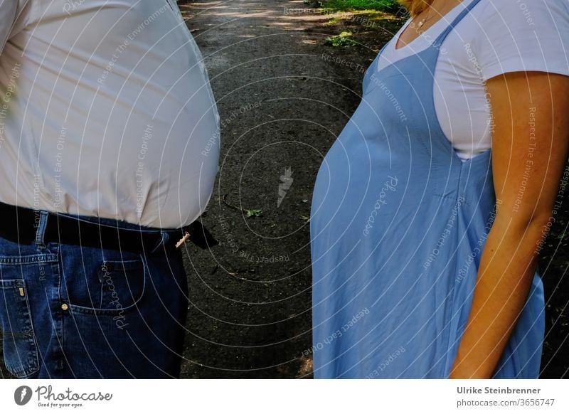 Old man and pregnant woman compete with her abdominal girth Bellies Stomach Fat Pregnant pregnancy Competition take measures thick maternity Woman Man Adults