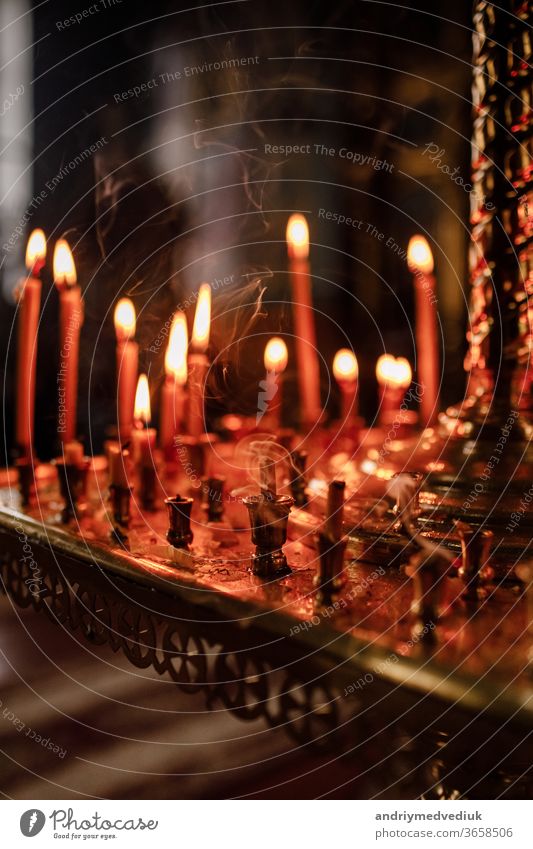 long lighted candles group in orthodox church. candles background. selective focus dark religion catholic wax christian symbol religious peace holiday yellow