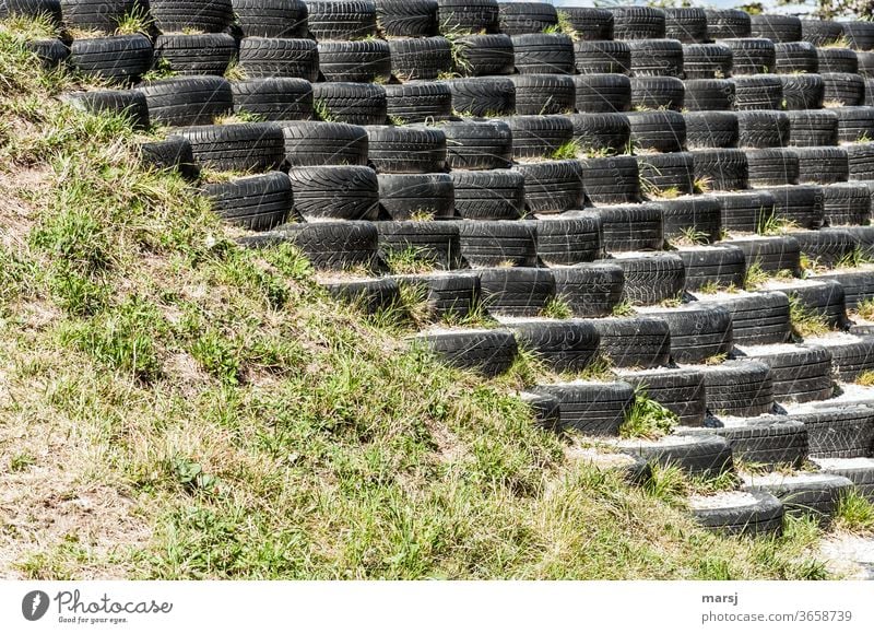 Old car tyre collection with little profile, built up in steps and diagonally divided with meadow Car tire scrap tyres Meadow Divided stagger Stairs Upward