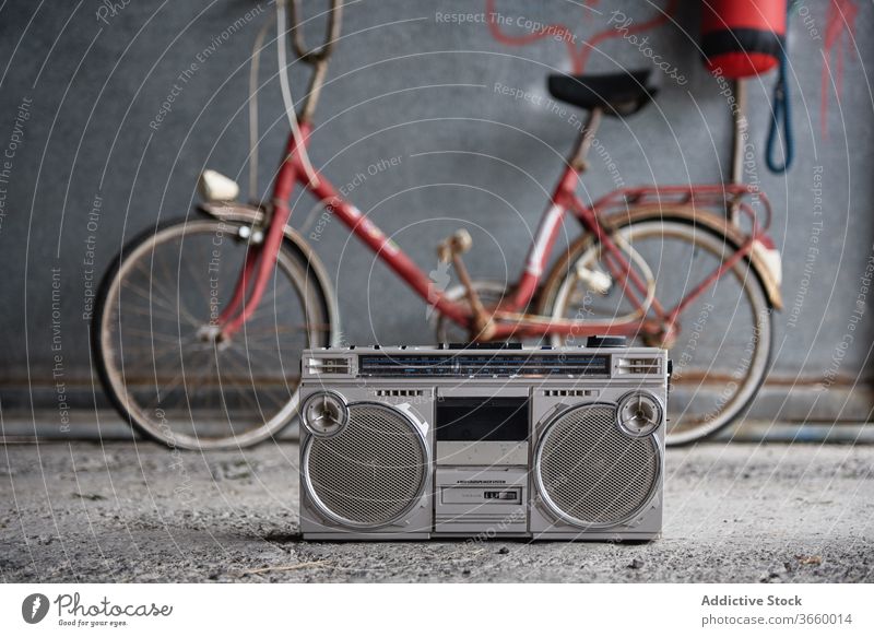 Retro boombox against bicycle in garage tape player single cassette old fashioned retro concrete floor obsolete portable nostalgia grunge gray shabby wall