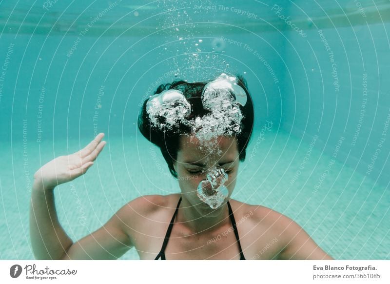 young woman diving underwater in a pool. summer and fun lifestyle swimming bubbles caucasian dive clear health light action wet swimmer blue active float person