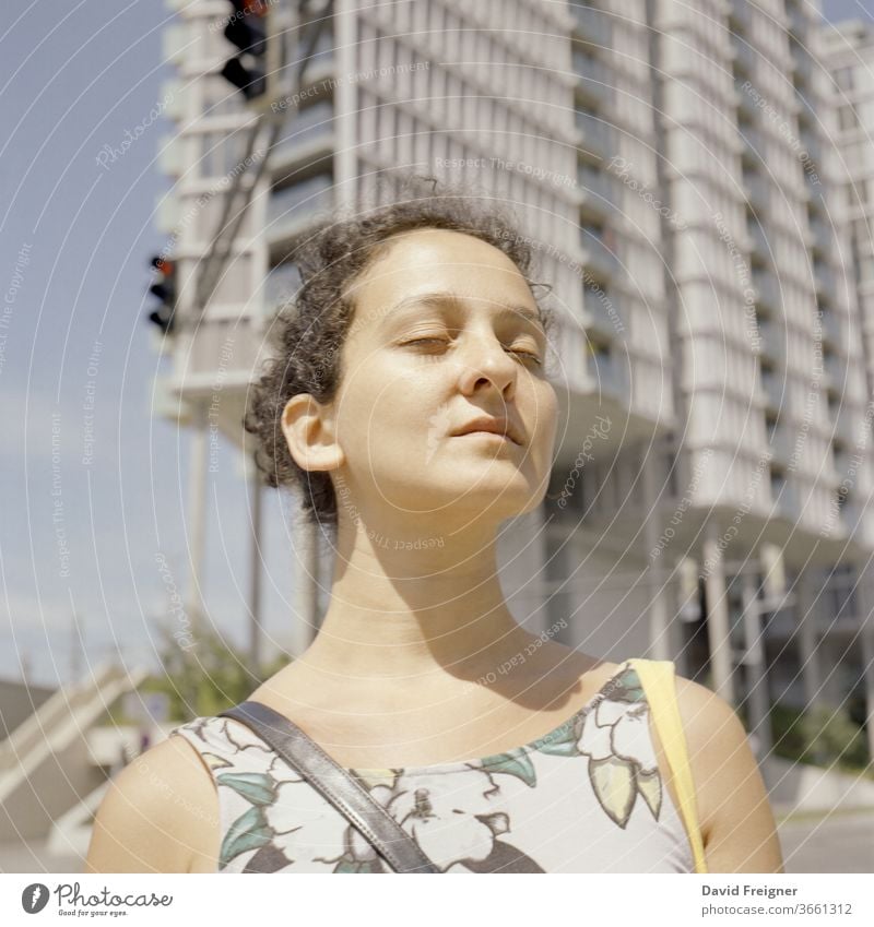 Young woman enjoys sun rays during a break. Contemplation and serenity concept. Shot on analog medium format film portrait young beauty beautiful face fashion