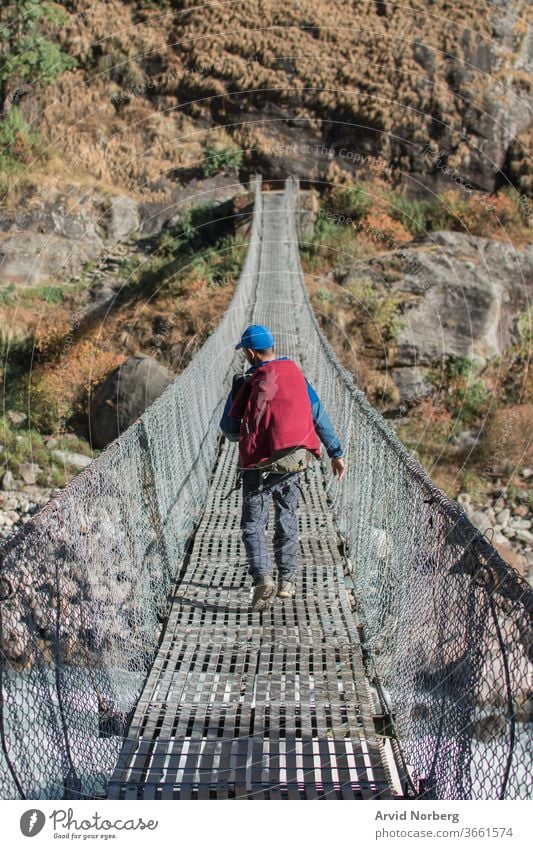 Adventurer trekking across a suspension bridge, Annapurna circuit, Nepal activity adventure along annapurna circuit backpack backpacker buddhism challenge