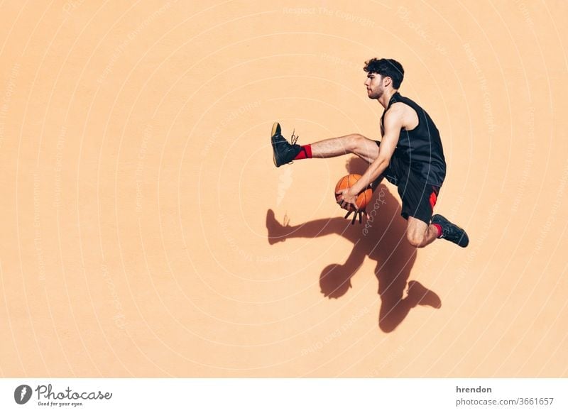 basketball player jumping with the ball in his hands in front of a wall sport competition motion game athletic competitive playing exercise male exercising