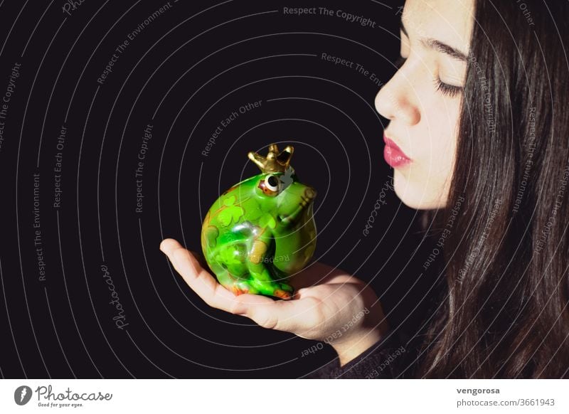Close-Up of young girl kissing a frog sculpture against black background Kissing teen teen girl teenage girl teenager one girl only brunette hair long hair