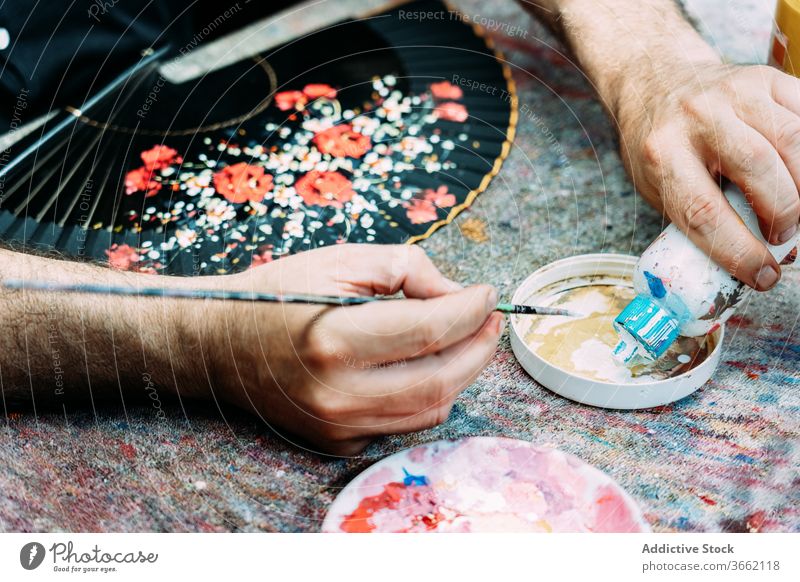 Crop artist pouring white gouache into palette while painting waver draw paintbrush artwork hand fan process floral pattern skill designer decor occupation
