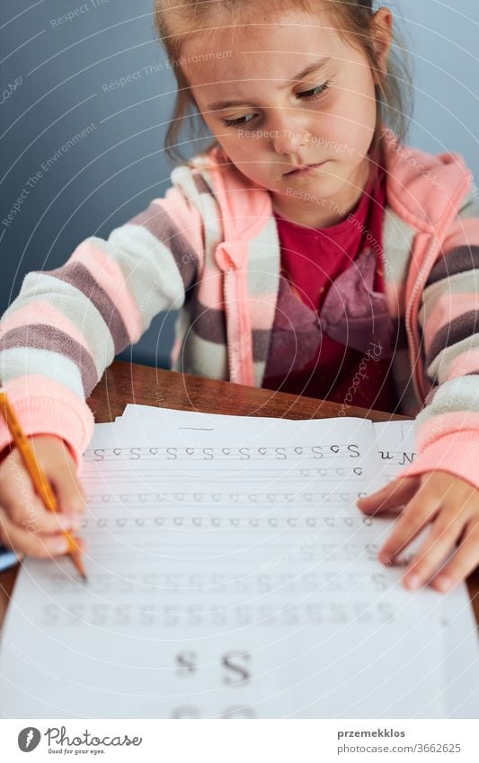 Little girl preschooler learning to write letters reluctantly. Kid writing letters, doing a school work unwillingly. Concept of early education attention