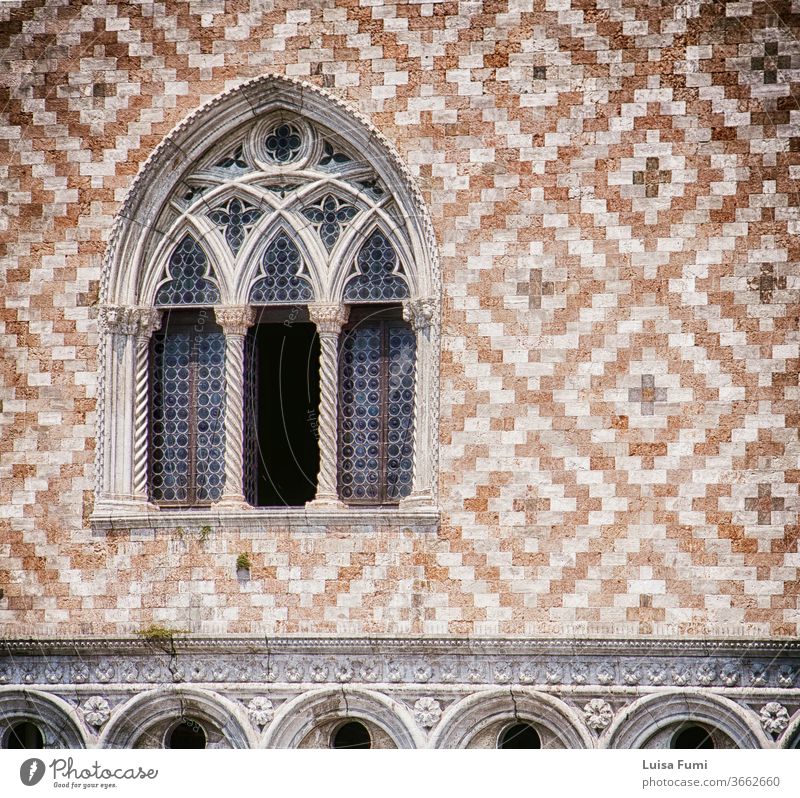 Venice, palazzo Ducale: detail of tripled arcade window and facade decoration with alternate red marble and white stone brick paving, soft focus Doge's Palace