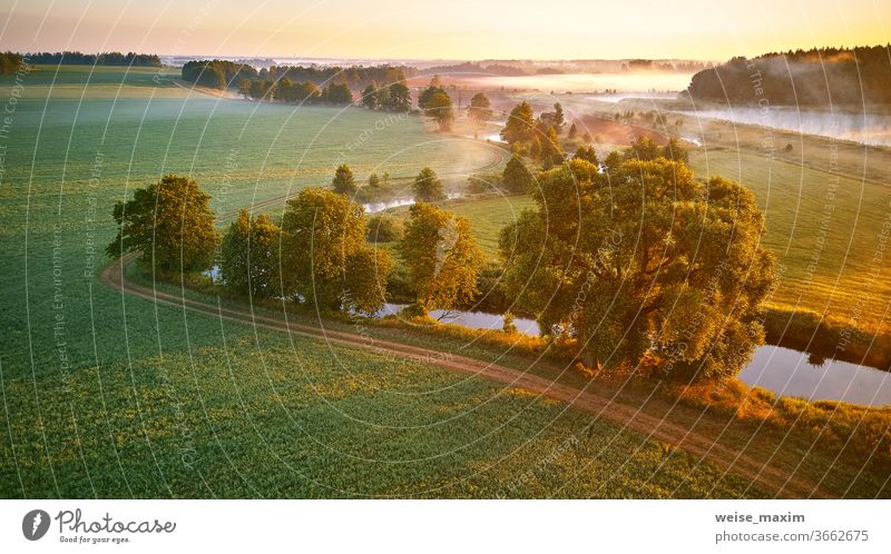 Sunny summer mist morning. First sunrays over green meadow and field fog river nature landscape sunrise cloud tree background environment panorama aerial creek